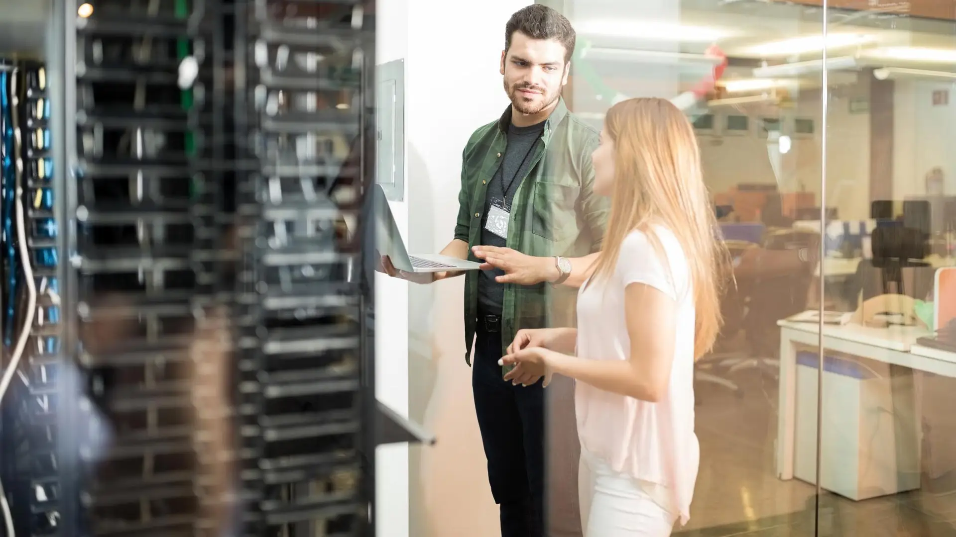 two business people standing server room with laptop discussing